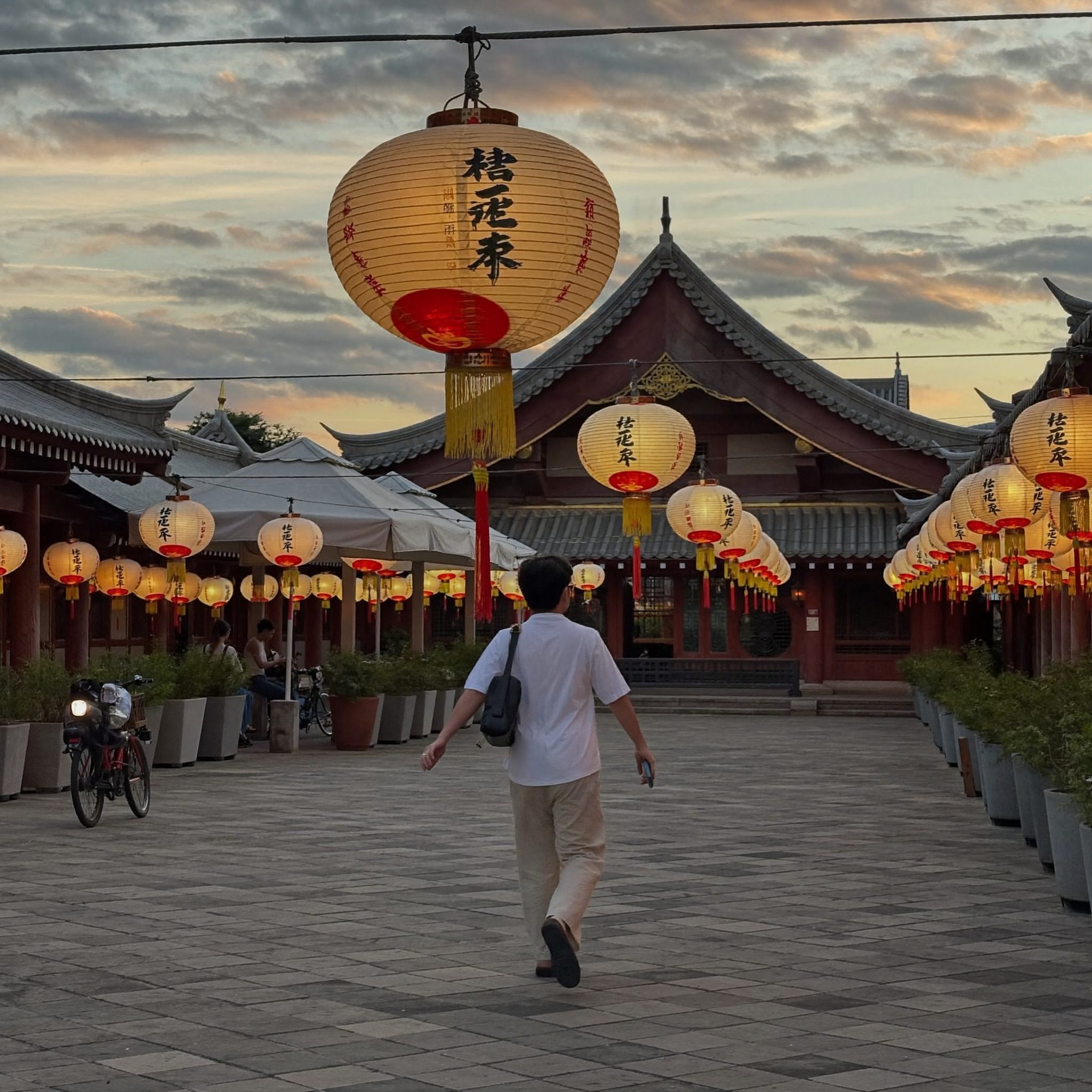 Voyageur près d'un temple asiatique illuminé de lanternes au crépuscule
